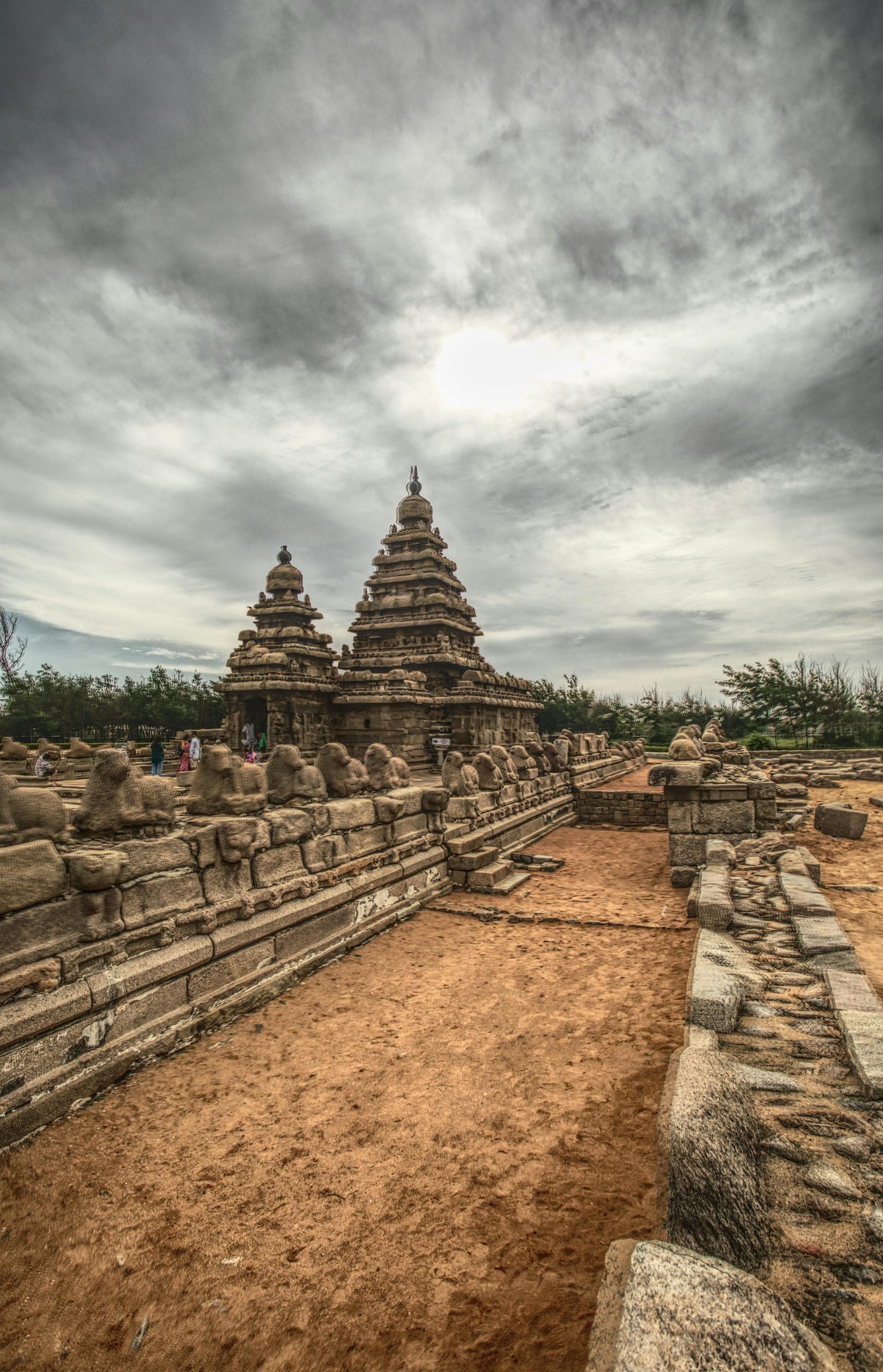 A dramatic view of the ancient Shore Temple in Mahabalipuram, India, under a moody sky.
